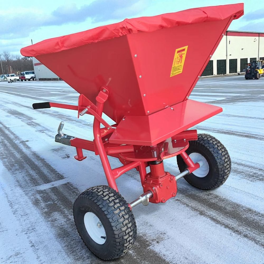 Forklift towing a salt spreader across an industrial car park in winter
