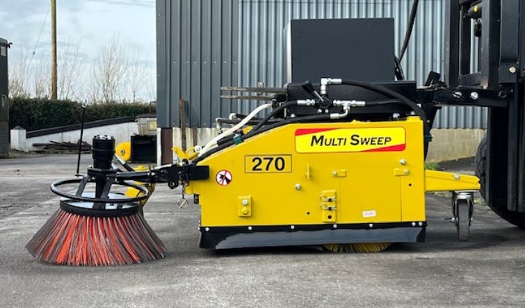 Forklift sweeper cleaning debris from an outdoor industrial yard