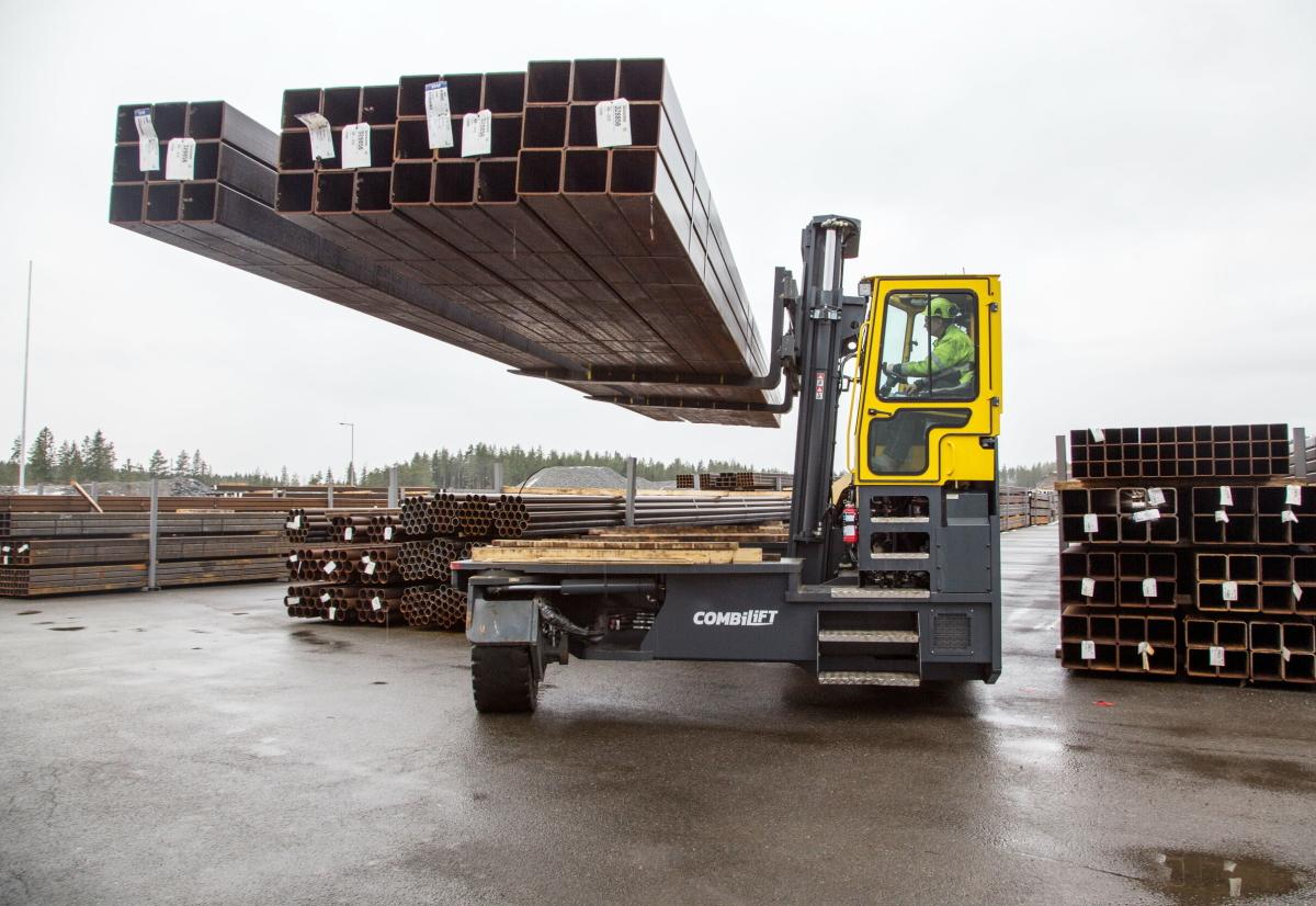 Forklift handling a long and awkward industrial load using a specialist attachment